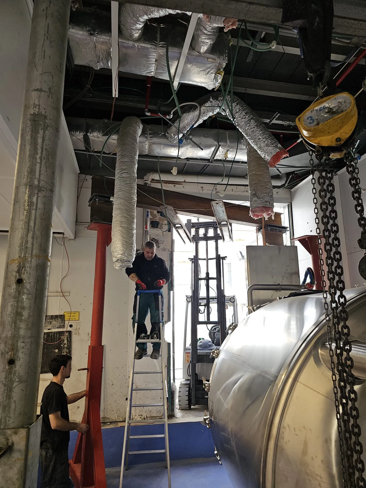 צוות מבצע ריגינג של ציוד תעשייתי עם שרשראות בתוך מפעל